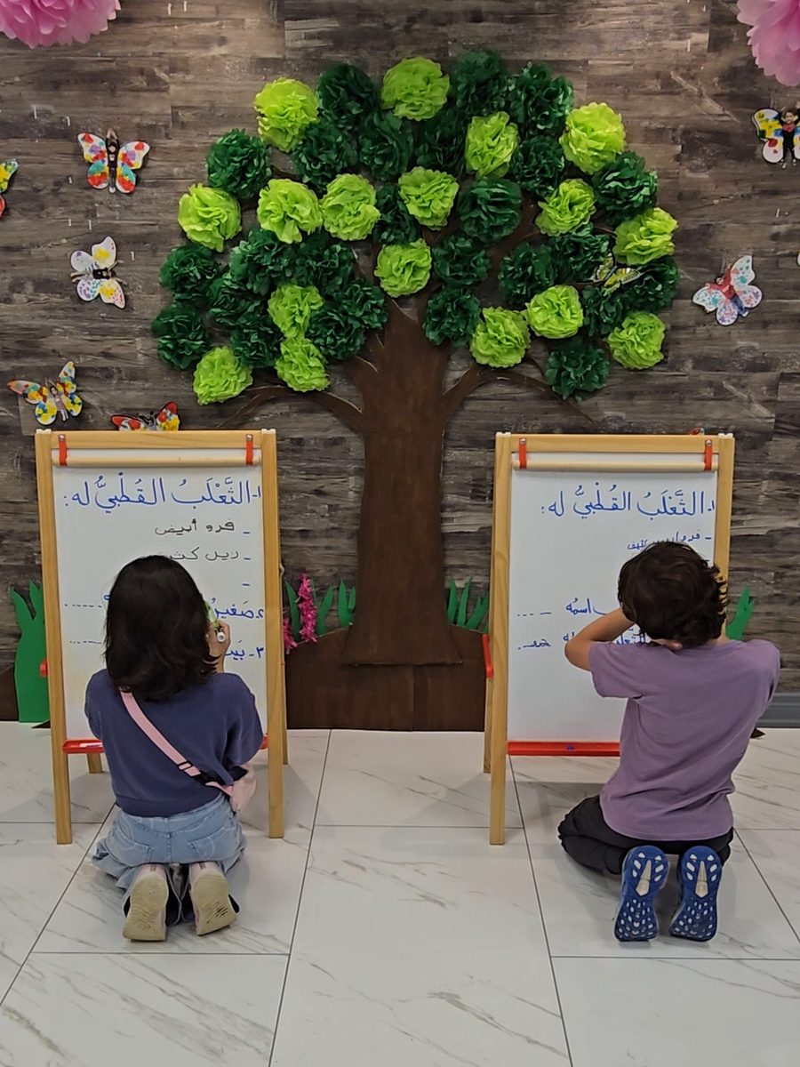 Two Arabeez students writing Arabic on whiteboard easels in the classroom