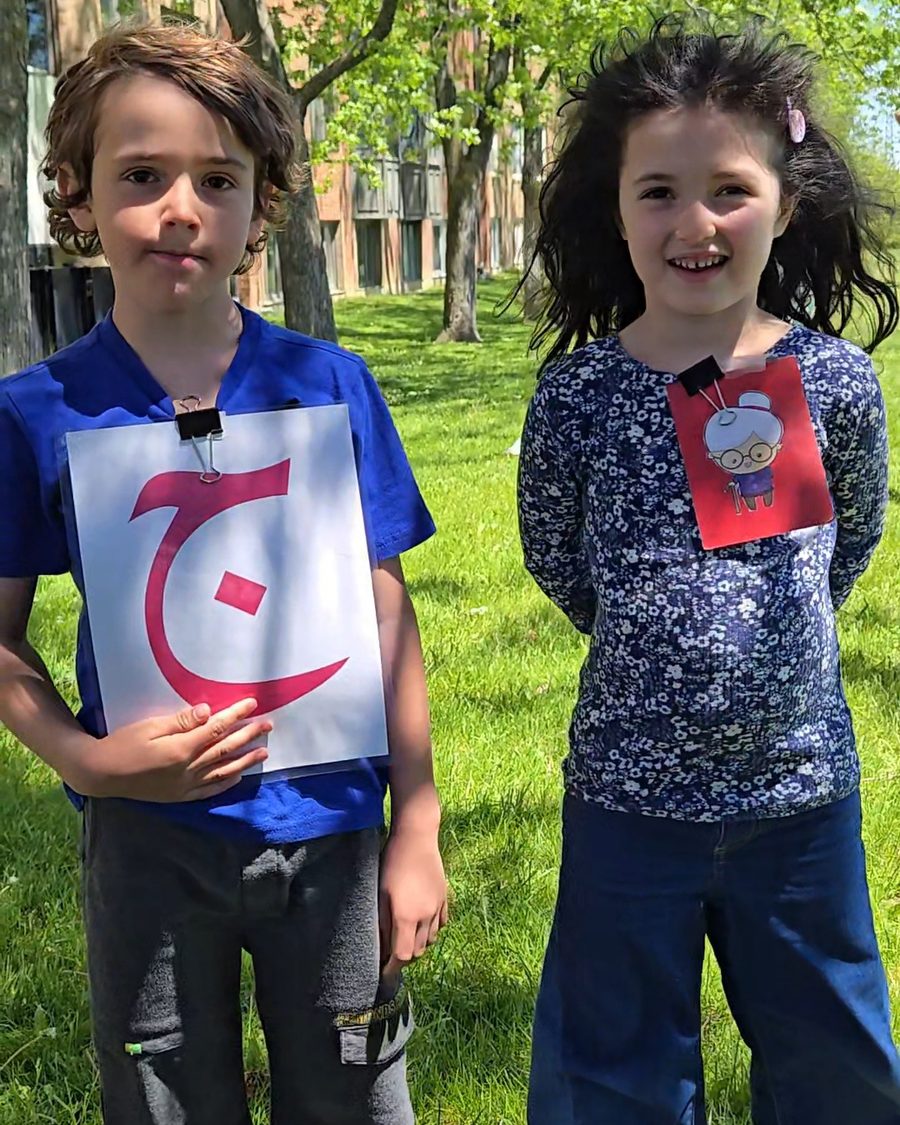 Two Arabeez students outdoors holding up the Arabic letters they are learning