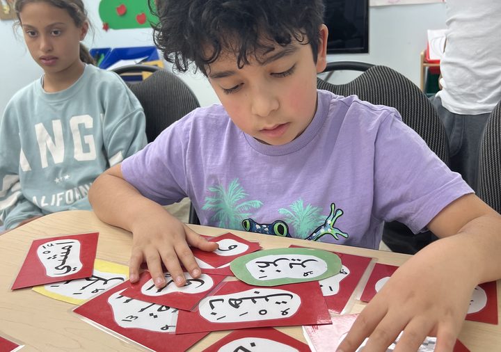 A student arranging Arabic word cards on his table